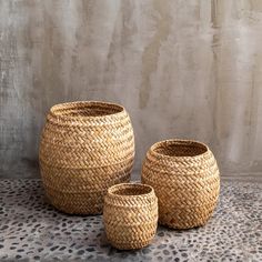 three woven baskets sitting next to each other on top of a tablecloth covered floor