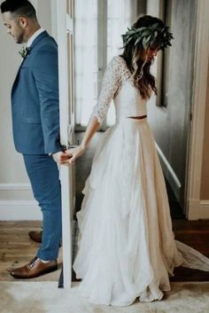 a man and woman standing in front of a door wearing wedding attire with flowers on their head