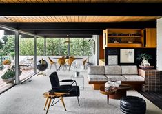 a living room filled with furniture and lots of glass doors leading to an outside deck