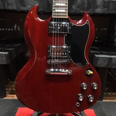 a red electric guitar sitting on top of a stand