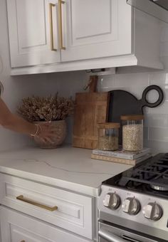 a woman is reaching for some food in a bowl on the kitchen counter next to an oven