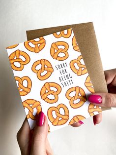 a woman holding up a card with some pretzels on it that says sorry for being salty