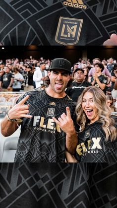 two people standing in front of a crowd at a sporting event with their arms around each other