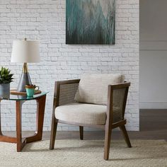 two chairs and a table in front of a white brick wall with a painting on it