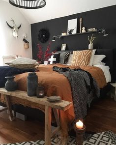 a bed room with a neatly made bed next to a night stand and some candles