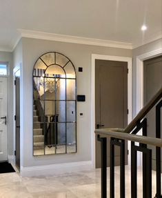 an entry way with a mirror on the wall and stairs leading to another room in the house