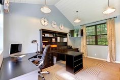 a home office with desk, computer monitor and clock mounted on the wall above it