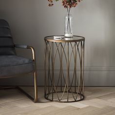 a glass vase sitting on top of a metal table next to a chair and lamp