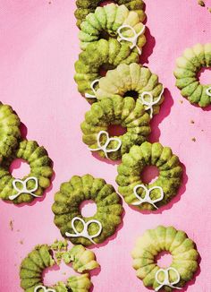 several green wreaths are arranged on a pink surface