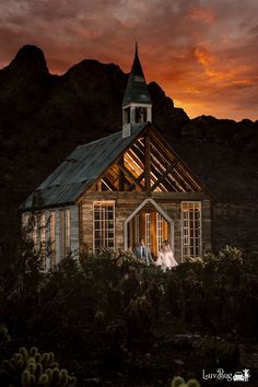 a bride and groom standing in front of an old church at sunset with mountains in the background