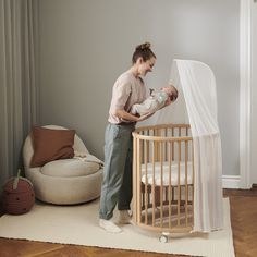 a woman standing next to a baby in a crib with a mosquito net over it