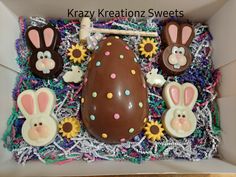 an easter egg decorated with chocolate bunny ears and sunflowers in a cardboard box