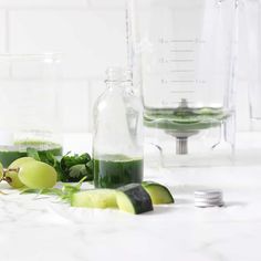 some green liquid is in a glass bottle and on the counter next to other ingredients