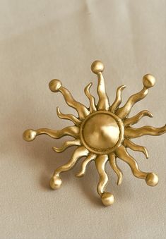 a gold sun brooch sitting on top of a table