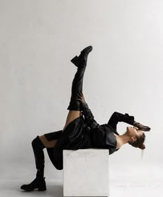 a woman laying on top of a white block with her legs spread out in the air