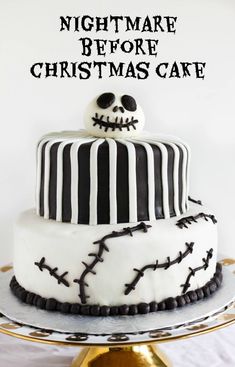 a white and black decorated cake on top of a gold platter with the words, nightmare before christmas cake