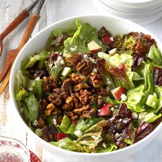 a salad with lettuce, walnuts, and dressing in a white bowl