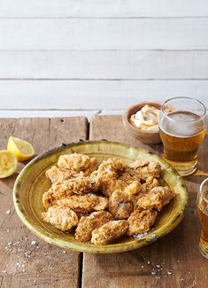 a table topped with two plates filled with food and three glasses full of beer next to each other