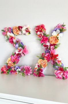 the letter k is made out of flowers on top of a white dresser with drawers