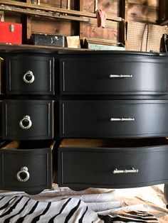 a black dresser with several drawers on it and a zebra print rug in the foreground