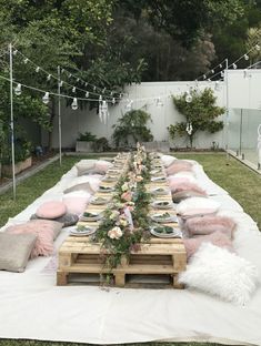 a long table is set up outside with pink pillows and blankets on the floor, along with other decorations