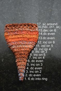 a crocheted orange and white cone sitting on top of a black countertop