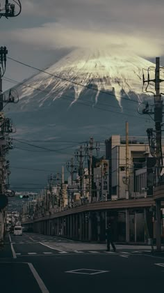 a city street with power lines and telephone poles in front of a snow covered mountain