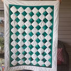 a green and white quilt hanging on a wall