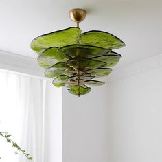 a green chandelier hanging from the ceiling in a room with white walls and windows