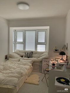 a bedroom with a bed, desk and window in it's corner area that has a record player on the floor