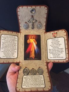 a person holding up a cross made out of paper with pictures and medals on it