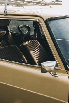 the interior of an old car with brown leather seats and steering wheel, in front of a mountain view