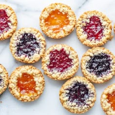 small pastries with jam on them sitting on a marble surface