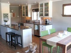 a dog sitting on the floor in a kitchen next to a dining table and chairs