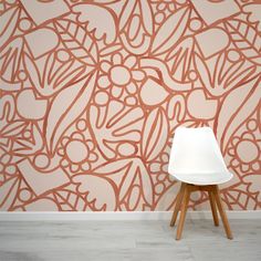 a white chair sitting in front of a wall with an orange and pink pattern on it