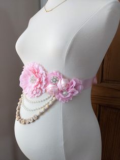 a white mannequin with pink flowers and pearls on it's belt,