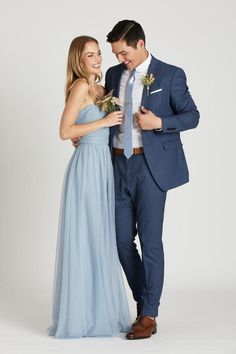 a man in a blue suit standing next to a woman wearing a light blue dress