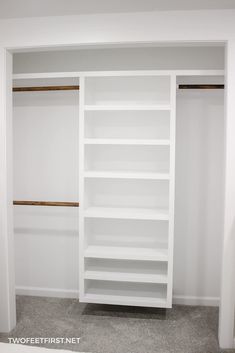 an empty closet with white shelving and wood trim on the walls, carpeted flooring