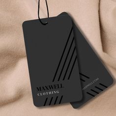 two black clothing tags hanging on a tan cloth with the words maxwell clothing written below them