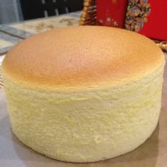 a round cake sitting on top of a table next to a red box and basket