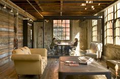 two people sitting at a table in an industrial style living room with exposed wood ceiling