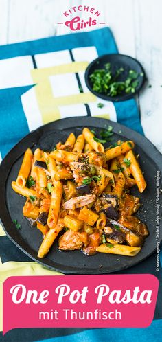 one pot pasta with mushrooms and parsley on a black plate next to a blue towel