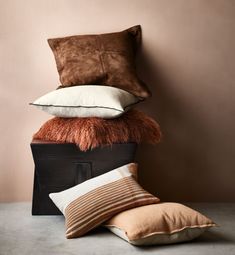 four pillows stacked on top of each other in front of a wall with a pink background