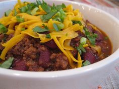 a white bowl filled with chili and cheese