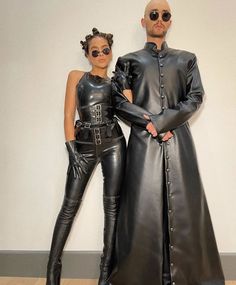 two people dressed in black leather standing next to each other with their hands on their hipss