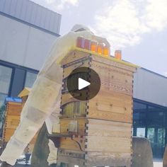 a man in bee suit walking next to a large wooden box filled with honeybees