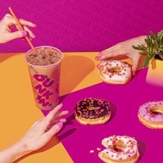 three donuts on a table with drinks and two hands reaching for one doughnut