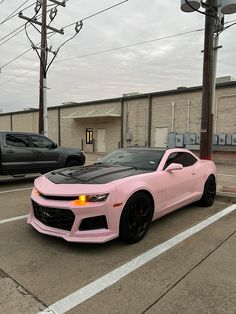 a pink chevrolet camaro parked in a parking lot