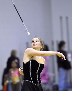 a woman in a black dress swinging a baseball bat