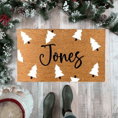 someone standing in front of a door mat with the word jones on it, surrounded by pine trees